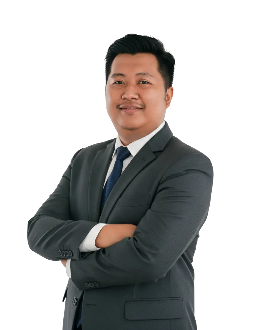 Ilham Saputra, arms crossed, in a charcoal suit and navy tie.